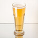 A Libbey Gibraltar footed pilsner glass of beer on a table.