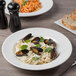 A white round porcelain entree and pasta bowl filled with creamy pasta and mussels.