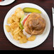 A Libbey white porcelain plate with a sandwich and potato chips on it.