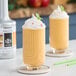 Two glasses of yellow drinks with white sprinkles on top.