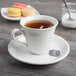 A Libbey white porcelain tea saucer with a cup of tea and cookies.