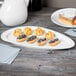 A table with a Libbey Royal Rideau white porcelain plate of chocolate covered pastries.