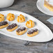 A chocolate covered eclair on a Libbey white porcelain plate.