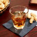 A Libbey Gibraltar Twist rocks glass of amber liquid with ice and peanuts on a napkin.