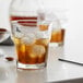 A Libbey Gibraltar double old fashioned glass with ice and amber liquid.