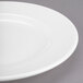 A close up of a Libbey white porcelain plate with a wide rim and curved edge.