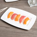 A piece of sushi on a Libbey Royal Rideau white rectangular plate with chopsticks.