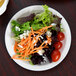 A close-up of a Libbey Slenda white plate with a salad with carrots and tomatoes.