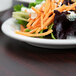 A Libbey white narrow rim footed porcelain plate with a salad and carrots on it.