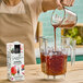 A woman pouring 1883 Maison Routin Wildberry Smoothie Mix into a blender.