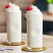 Two glasses of Cappuccine Supreme White Chocolate milkshakes with whipped cream and raspberries.