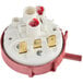 A close up of a red and white pressure switch with two red wires.