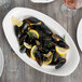 A Libbey white porcelain platter with mussels and lemon wedges.