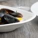 A Libbey white porcelain platter with mussels and lemon wedges on a table.