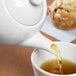 A white Libbey Slenda tea pot pouring tea into a white tea cup.