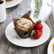 A muffin and strawberries on a Libbey white wide rim porcelain plate.