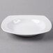 A Libbey Slenda white square porcelain deep rimmed soup bowl on a gray surface.