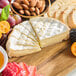 A cheese and fruit platter with Eiffel Tower Camembert cheese, bread, and nuts.