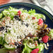 A salad with berries and Celebrity Goat crumbled goat cheese on a plate.