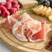A platter with Fontana Ermes DOP thin-sliced Italian Prosciutto di Parma, raspberries, and nuts.