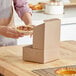 A person holding a pecan pie in a Southern Champion kraft pie box.