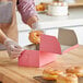 A woman putting a donut into a pink Southern Champion bakery box.