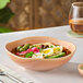 A table set with Acopa Highlands Primrose Peach china bowls filled with food.