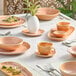An oblong peach coupe tray with white dishes and cups on a table.