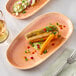 An Acopa Primrose Peach coupe china tray with a plate of food, a fork, and a glass of wine on a table.