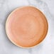 An Acopa Highlands Primrose Pink coupe plate with a small hole in the center.