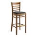 A Lancaster Table & Seating wooden ladder back bar stool with black vinyl seat.