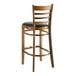 A Lancaster Table & Seating wooden bar stool with a black vinyl seat.