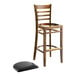 A Lancaster Table & Seating wood ladder back bar stool with a black vinyl seat.