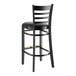 A Lancaster Table & Seating black wood ladder back bar stool with a black vinyl seat.