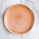 An Acopa Highlands Primrose Pink coupe china plate on a marble surface.