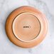An Acopa Highlands Primrose Pink coupe china plate on a marble surface.