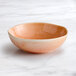 An Acopa Highlands primrose pink china bowl on a marble surface.