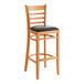 A Lancaster Table & Seating wood ladder back bar stool with a black vinyl seat detached.