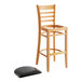 A Lancaster Table & Seating wooden bar stool with a detached black vinyl seat pad.