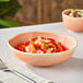 An Acopa Highlands Primrose Peach china bowl filled with food and vegetables on a table.