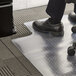A person sitting in a black office chair on a clear lipped office chair mat.