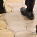 The feet of a person wearing black shoes on a 36" x 48" clear plastic office chair mat.