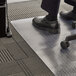 A person standing on a 360 clear plastic office chair mat with black shoes.