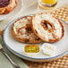 A plate of bagels with Sommer Maid whipped butter and a jar of jam on a table.