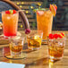 Acopa Memphis glasses filled with orange liquid, ice, and orange slices on a table.