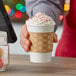 A hand using a snowflake printed coffee cup sleeve to hold a cup of coffee.