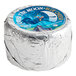 A round silver package of Over the Moon Blue Cheese with a blue label featuring a cow and a moon.