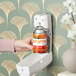 A person putting a F-Matic Citrus Sunburst air freshener refill into a wall-mounted air freshener.