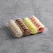 A plastic container holding a variety of Macaron Centrale vegan macarons in different colors.