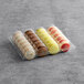 A plastic container holding a variety of Macaron Centrale vegan macarons with different colors.